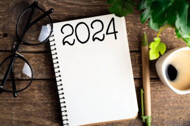 2024 sayılı yeni yıl kararları masada. 2024 gol listesi, defter, kahve fincanı, ahşap masa. Kararlar, plan, hedefler, eylem, kontrol listesi, fikir konsepti. Yeni Yıl 2024 Kararları