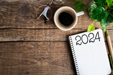2024 sayılı yeni yıl kararları masada. 2024 gol listesi, defter, kahve fincanı, ahşap masa. Kararlar, plan, hedefler, eylem, kontrol listesi, fikir konsepti. Yeni Yıl 2024 Kararları