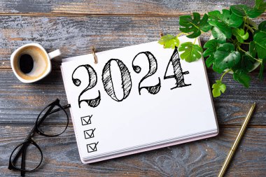 2024 sayılı yeni yıl kararları masada. 2024 gol listesi, defter, kahve fincanı, ahşap masa. Kararlar, plan, hedefler, eylem, kontrol listesi, fikir konsepti. Yeni Yıl 2024 Kararları
