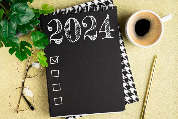 New year resolutions 2024 on desk. 2024 resolutions list with notebook, coffee cup on table. Goals, resolutions, plan, action, checklist concept. New Year 2024 template. Copy space