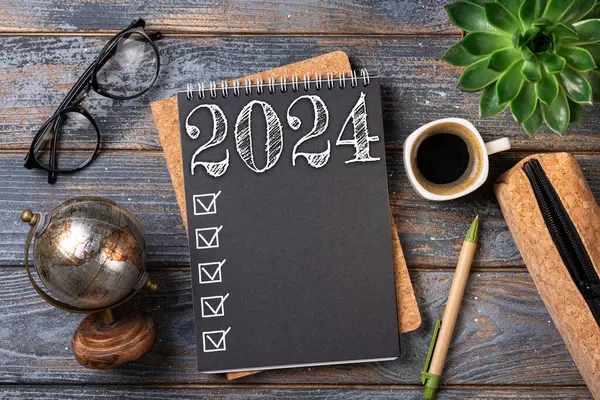 New year resolutions 2024 on desk. 2024 goals list with notebook, coffee cup, plant on wooden table. Resolutions, plan, goals, action, checklist, idea concept. New Year 2024 resolutions, copy space