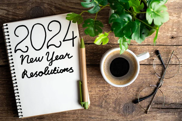 新年の決議2024が机の上に ノートブック コーヒーカップ 木のテーブルに植える2024ゴールリスト チェックリスト アイデアコンセプト 新年2024決議 ロイヤリティフリーのストック写真