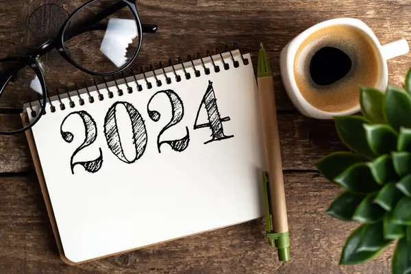 新年の決議2024が机の上に ノートブック コーヒーカップ 木のテーブルに植える2024ゴールリスト チェックリスト アイデアコンセプト 新年2024決議 ストック写真