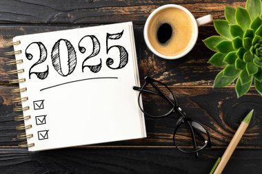 Yeni yıl kararları 2025 masada. 2025 gol listesi, defter, kahve fincanı, ahşap masa. Kararlar, plan, hedefler, eylem, kontrol listesi, fikir konsepti. Yeni yıl 2025 kararları. Boşluğu kopyala