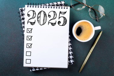 Yeni yıl kararları 2025 masada. Not defteri ve kahve fincanı olan 2025 karar listesi. Hedefler, çözümler, plan, eylem, kontrol listesi konsepti. Yeni Yıl 2025 şablonu, kopyalama alanı