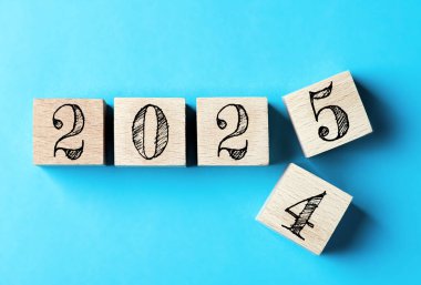 2025 mutlu yıllar. 2024 'ten 2025' e kadar mavi üzerine tahta blok değişimi. 2025 'in yeni yıl geçmişi. İş, kararlar, hedefler, ilham, başarı, fikirler