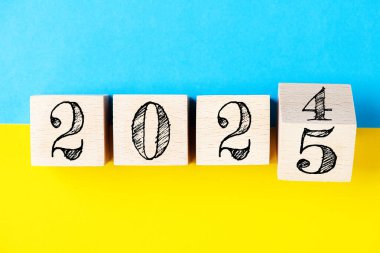 2025 Mutlu yıllar konsepti. 2024 'ten 2025' e kadar sarı ve mavi arkaplan Ukrayna bayrağında tahta blok değişimi. Siyaset, Ukrayna 'ya destek, çözümler, hedefler, iş dünyası, başarı fikirlerine ilham