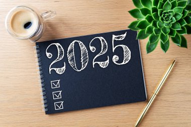 Yeni yıl kararları 2025 masada. 2025 gol listesi, defter, kahve fincanı, ahşap masa. Kararlar, plan, hedefler, eylem, kontrol listesi, fikir konsepti. Yeni Yıl 2025 kararları, kopyalama alanı