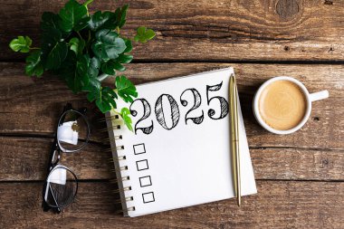 Yeni yıl kararları 2025 masada. 2025 gol listesi, defter, kahve fincanı, ahşap masa. Kararlar, plan, hedefler, eylem, kontrol listesi, fikir konsepti. Yeni Yıl 2025 kararları, kopyalama alanı