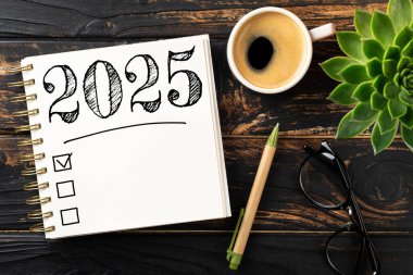 Yeni yıl kararları 2025 masada. Not defterli 2025 karar listesi, ahşap masadaki kahve fincanı. Hedefler, çözümler, plan, eylem, kontrol listesi konsepti. Yeni Yıl 2025 şablonu, kopyalama alanı