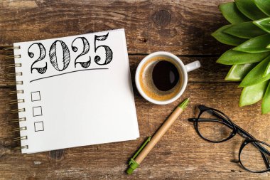 Yeni yıl kararları 2025 masada. 2025 gol listesi, defter, kahve fincanı, ahşap masa. Kararlar, plan, hedefler, eylem, kontrol listesi, fikir konsepti. Yeni Yıl 2025 şablonu, kopyalama alanı