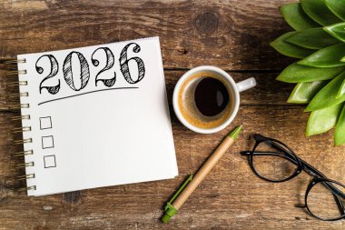 2026 sayılı yeni yıl kararları masada. 2026 gol listesi, defter, kahve fincanı, ahşap masa. Kararlar, plan, hedefler, eylem, kontrol listesi, fikir konsepti. Yeni Yıl 2026 şablonu, Spac kopyala