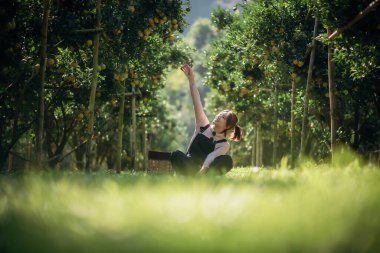 Mutlu bir kadın çiftçi meyve bahçesinde ya da portakal çiftliğinde dinleniyor..