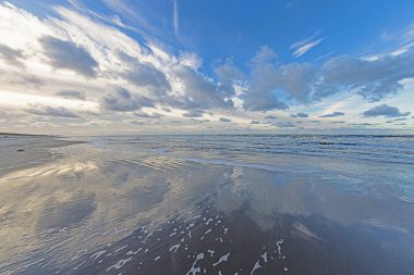 Danimarka 'da Vejers yakınlarındaki bir Kuzey Denizi sahilinin kış görüntüsü. Sörf ve etkileyici bulut oluşumları var.