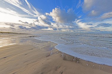 Danimarka 'da Vejers yakınlarındaki bir Kuzey Denizi sahilinin kış görüntüsü. Sörf ve etkileyici bulut oluşumları var.