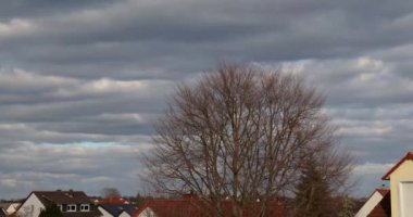 Kışın günbatımında bir yerleşim yerinin üzerinde alçak hareket eden bulutların yer aldığı hızlandırılmış bir film