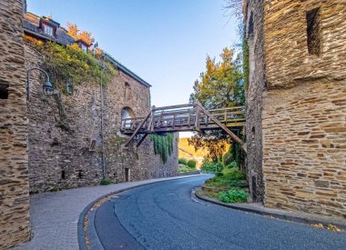 Gündüz vakti Alman Orta Ren Vadisi 'nde tahta köprüsü olan tarihi bir şatonun dış duvarı boyunca uzanan bir yolun görüntüsü.