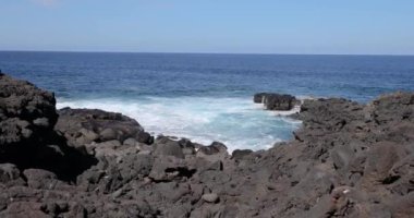 Gündüz vakti Lanzarote 'deki El Golfo yakınlarındaki volkanik kıyılarda sörf videosu.