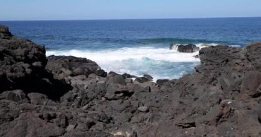 Gündüz vakti Lanzarote 'deki El Golfo yakınlarındaki volkanik kıyılarda sörf videosu.