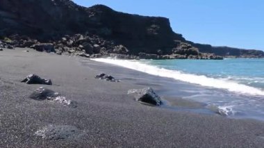 Gündüz vakti Lanzarote 'deki El Golfo yakınlarındaki volkanik kıyılarda sörf videosu.
