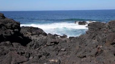 Gündüz vakti Lanzarote 'deki El Golfo yakınlarındaki volkanik kıyılarda sörf videosu.
