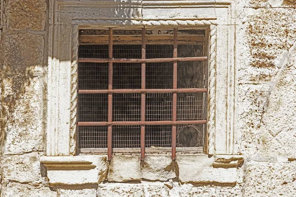 Picture of an old barred window with rusty bars in the sunlight during the day