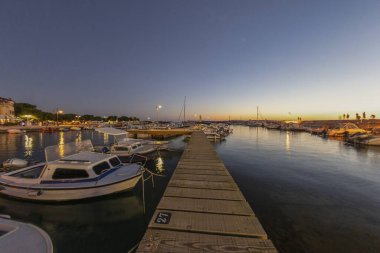 Hırvatistan 'ın Fazana kıyı köyünün limanında gün batımında yaz akşamları tekne iskelesi üzerinde güneş batıyor.