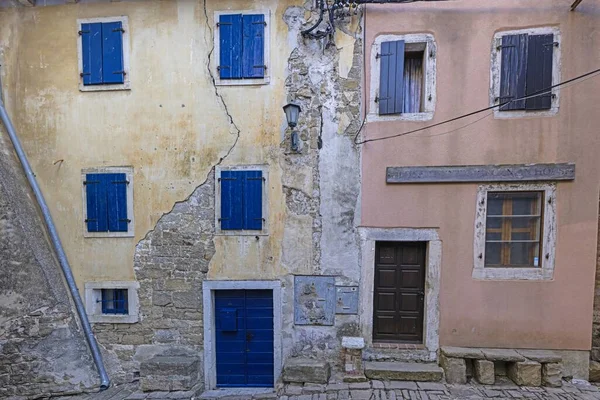 Picture of an colored plaster facade of an old building in need of renovation during daytime