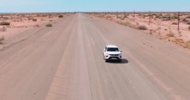 Namibya 'daki Namibya' daki Namib-Naukluft Ulusal Parkı 'nın kenarındaki çölde çakıllı bir yolda hareket halindeki bir aracın videosu.