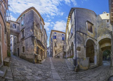 Yüksek binalara giden kaldırım taşlı bir yolun geniş açılı balık bakışı görüntüsü.