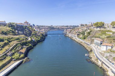 Büyük bir su kütlesi boyunca uzanan bir köprü manzarası. Her iki yakada da küçük evler görülebiliyor.