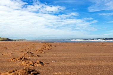Yaz aylarında İskoçya 'da kum tepeleri ve ayak izleri olan terk edilmiş bir sahil resmi.