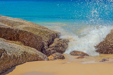 Gün ışığında kumlu bir sahilde aşırı gelişmiş taşların yakın çekimi.