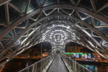 Peace Bridge in Tbilisi, Georgia, illuminated at night over the Kura River, captured in artificial light in summer clipart