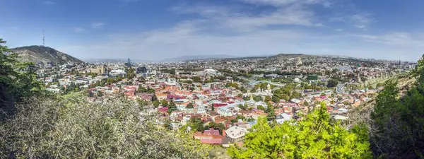 Gürcistan 'ın Tiflis kentindeki panoramik gündüz manzarası, gün boyunca renkli çatılar ve simgelerle