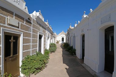 The Cimiteriu Marinu di Bunifaziu near Bonifacio, Corsica, with ornate white tombs and a central monument under a clear sky during daytime clipart