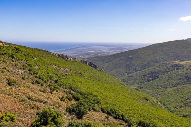 Korsika 'nın doğu kıyı şeridinin panoramik görüntüsü gün boyunca verimli yeşilliklerle dolu dağlık iç kesimlerden yakalandı.