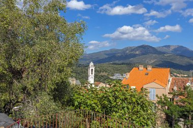 Corte 'nin tarihi eski kasabası Korsika' da gün içinde dükkanları, kilisesi ve kaldırım taşları olan büyüleyici bir sokak manzarası.