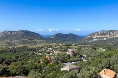 Korsika 'daki Cardeto köyünün gündüz vakti dalgalı tepeleri ve denizi ile panoramik görüntüsü