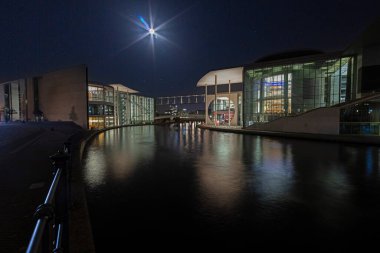 Berlin hükümet bölgesinin aydınlanmış modern mimarisi kışın Spree 'ye yansıyor.