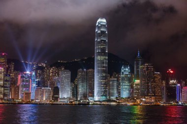 Panoramic nighttime view of illuminated Hong Kong skyline reflected in the water with vibrant city lights in summer clipart