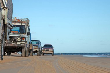 Off-road vehicles on Fraser Island beach with ocean waves and sandy track during daytime clipart