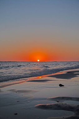 Canlı turuncu gökyüzü, yumuşak dalgalar ve Florida 'daki sakin sahil şeridiyle nefes kesici okyanus batımı.
