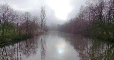 Sisli bir günde, Frankfurt 'taki Nidda Nehri üzerinde insansız hava aracı uçuşu. Sakin su yansımaları ve kışın sisli bir atmosfer.