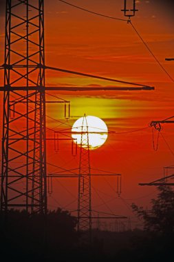 Güç iletim kuleleri gün batımına karşı siluetlendi