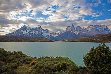 Gündüz vakti Torres del Paine 'deki dramatik dağların ve geniş gökyüzünün yansımalarıyla Pehoe Gölü' nün panoramik görüntüsü