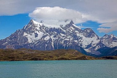 Gündüz vakti Torres del Paine 'deki dramatik dağların ve geniş gökyüzünün yansımalarıyla Pehoe Gölü' nün panoramik görüntüsü