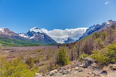 Cerro Torre ve gündüz çevresindeki tepelerle Laguna Torre 'a doğru vadi manzarası