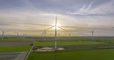 Rüzgar çiftliğinin batan güneşe karşı zamanı çarpıcı hareket eden bulutlar ve gün batımında değişen ışık