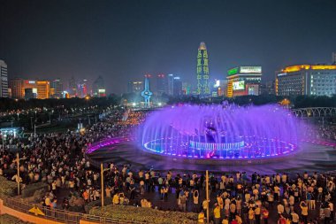 Illuminated fountain show at Quancheng Square in Jinan China with crowds at night in summer clipart